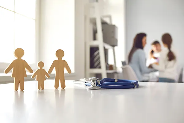 Wooden family figures beside a stethoscope in a primary care clinic.