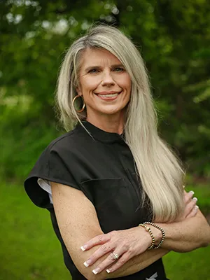 A smiling woman with long hair posing outdoors.
